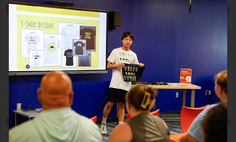 A student presents his T-shirt designs to an audience at the Design Lab showcase.